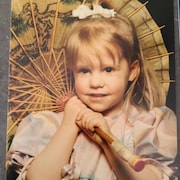 Une petite fille de moins de 10 ans pose avec une ombrelle japonaise.